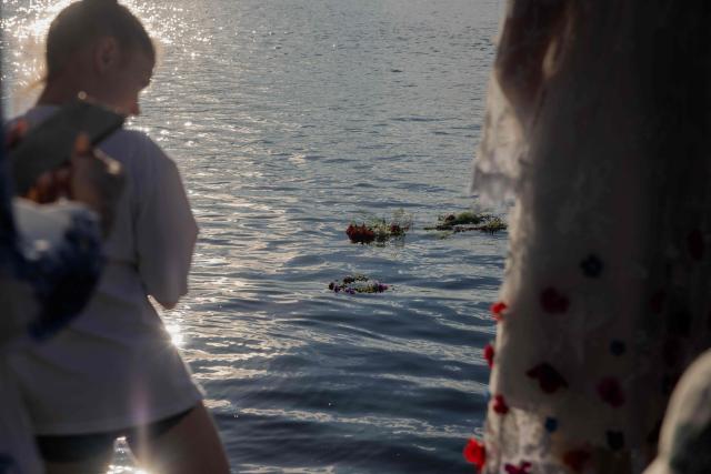 Flower wreaths float on the water during a picnic in the spirit of the Ivan Kupala holiday organized by the Veterans Corps for soldiers, veterans, and their families in Kyiv on June 20, 2026, amid the Russian invasion of Ukraine. (Photo by Tetiana DZHAFAROVA / AFP)
