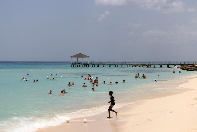 People bathe in the sea on a beach in Bayahibe, La Altagracia province, Dominican Republic, on July 20, 2026, following a fire at the Viva Dominicus Beach hotel. An Italian tourist died on June 19 after inhaling smoke from a large fire at a hotel in the resort town of Bayahibe, southeastern Dominican Republic, an official told AFP. (Photo by Erickson Polanco / AFP)
