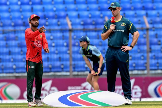 Bangladesh's captain Towhid Hridoy (L) tosses the coin as his Australian counterpart Mitchell Marsh watches before the start of the third Twenty20 (T20) international cricket match between Bangladesh and Australia at the Bir Sreshtho Flight Lieutenant Matiur Rahman Stadium in Chattogram on June 21, 2026. (Photo by AFP)