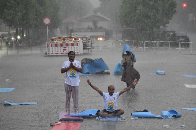 Unwavering yoga enthousiasts brave the pouring rain as they take part in the international yoga day, on June 21, 2026 in Berlin, Germany. (Photo by RALF HIRSCHBERGER / AFP)
