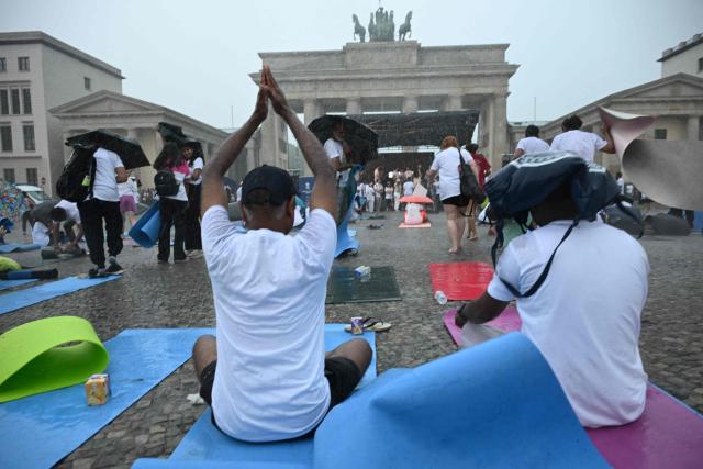 Unwavering yoga enthousiasts brave the pouring rain as they take part in the international yoga day, on June 21, 2026 at the Brandenburg Gate in Berlin, Germany. (Photo by RALF HIRSCHBERGER / AFP)