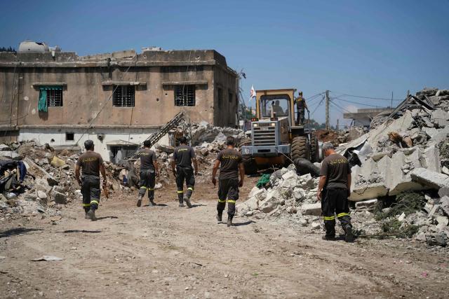 Lebanese civil defence workers walk behind a bulldozer as it removes the rubble from the main market place destroyed by the Israeli military in the southern city of Nabatieh on June 21, 2026. The first round of negotiations between the United States and Iran since the two sides signed a preliminary agreement to halt their war was due to begin in Switzerland on June 21, with the conflict in Lebanon threatening the deal. Lebanon was drawn into the Middle East war on March 2 when Tehran-backed militant group Hezbollah launched attacks on Israel to avenge the killing of the Iranian leader. Israel has responded with broad strikes across Lebanon and a ground offensive. (Photo by Abbas FAKIH / AFP) / 