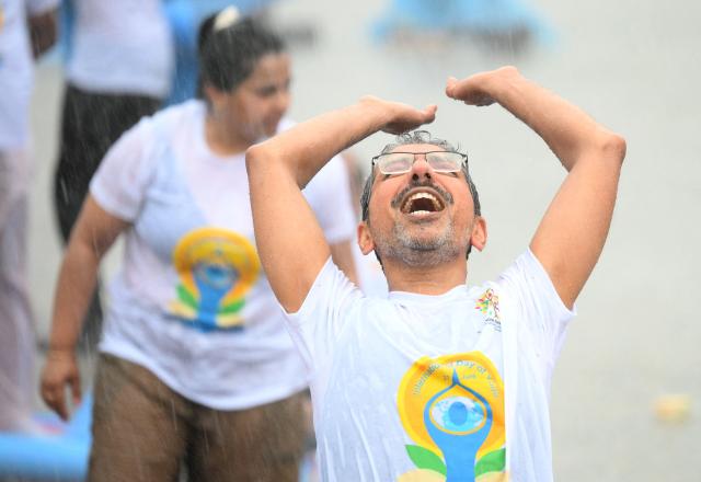 An unwavering yoga enthousiast braves the pouring rain as he takes part in the international yoga day, on June 21, 2026 in Berlin, Germany. (Photo by RALF HIRSCHBERGER / AFP)