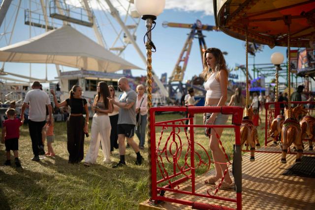 A stall holder waits for customers by their ride at The Hoppings fun fair, believed to be one of the largest travelling funfairs in Europe, in Newcastle upon Tyne, north east England on June 20, 2026. The fun fair, which originally began as a Temperance Fair in 1882, comprises of over 400 attractions set up on the city's Town Moor. The fair runs until June 28, 2026 and is expected to attract around 500,000 people. (Photo by Oli SCARFF / AFP)