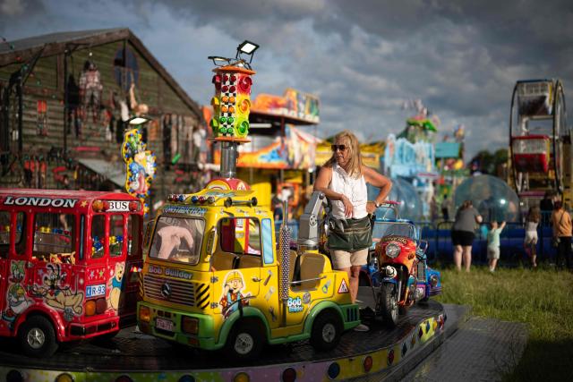 A stall holder waits for customers by their ride at The Hoppings fun fair, believed to be one of the largest travelling funfairs in Europe, in Newcastle upon Tyne, north east England on June 20, 2026. The fun fair, which originally began as a Temperance Fair in 1882, comprises of over 400 attractions set up on the city's Town Moor. The fair runs until June 28, 2026 and is expected to attract around 500,000 people. (Photo by Oli SCARFF / AFP)