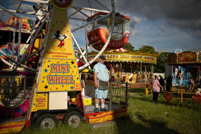 A stall holder waits for customers by their ride at The Hoppings fun fair, believed to be one of the largest travelling funfairs in Europe, in Newcastle upon Tyne, north east England on June 20, 2026. The fun fair, which originally began as a Temperance Fair in 1882, comprises of over 400 attractions set up on the city's Town Moor. The fair runs until June 28, 2026 and is expected to attract around 500,000 people. (Photo by Oli SCARFF / AFP)