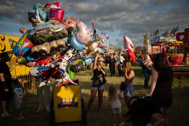 Members of the public buy novelty balloons as they attend The Hoppings fun fair, believed to be one of the largest travelling funfairs in Europe, in Newcastle upon Tyne, north east England on June 20, 2026. The fun fair, which originally began as a Temperance Fair in 1882, comprises of over 400 attractions set up on the city's Town Moor. The fair runs until June 28, 2026 and is expected to attract around 500,000 people. (Photo by Oli SCARFF / AFP)