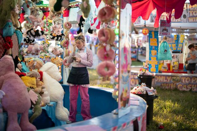 A stall holder waits for customers by their game at The Hoppings fun fair, believed to be one of the largest travelling funfairs in Europe, in Newcastle upon Tyne, north east England on June 20, 2026. The fun fair, which originally began as a Temperance Fair in 1882, comprises of over 400 attractions set up on the city's Town Moor. The fair runs until June 28, 2026 and is expected to attract around 500,000 people. (Photo by Oli SCARFF / AFP)