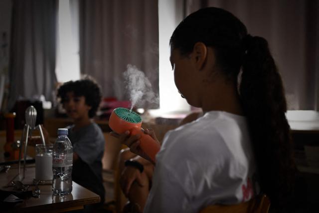(FILES) A child keeps cool using a portable fan as she attends class in an elementary school during a heatwave in Bordeaux, south-western France on July 1, 2025. A total of 845 primary and secondary schools will be closed on June 21, 2026 in France due to the heatwave, whilst a further 1,800 schools will "adjust their timetables", meaning they will "dismiss pupils in the early afternoon", France's Education Minister announced on June 21, 2026. (Photo by Philippe LOPEZ / AFP)