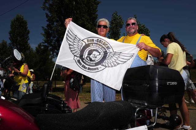 Attendees hold a flag reading Run Coluche, moto party, open bike memory" as they take part in a "Run Coluche" biker gathering as part of a tribute to French comedian and actor Coluche 40 years after his death, in Opio, southeastern France, on June 21, 2026. (Photo by Valery HACHE / AFP)