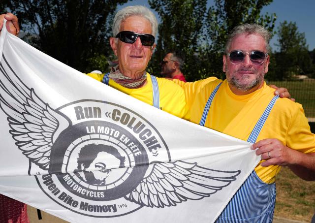 Attendees hold a flag reading Run Coluche, moto party, open bike memory" as they take part in a "Run Coluche" biker gathering as part of a tribute to French comedian and actor Coluche 40 years after his death, in Opio, southeastern France, on June 21, 2026. (Photo by Valery HACHE / AFP)