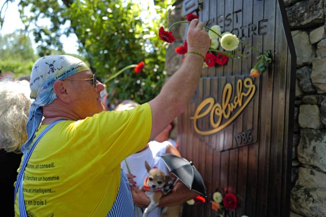 An attendee places a flower on a memorial during a "Run Coluche" biker gathering as part of a tribute to French comedian and actor Coluche 40 years after his death, in Opio, southeastern France, on June 21, 2026. (Photo by Valery HACHE / AFP)