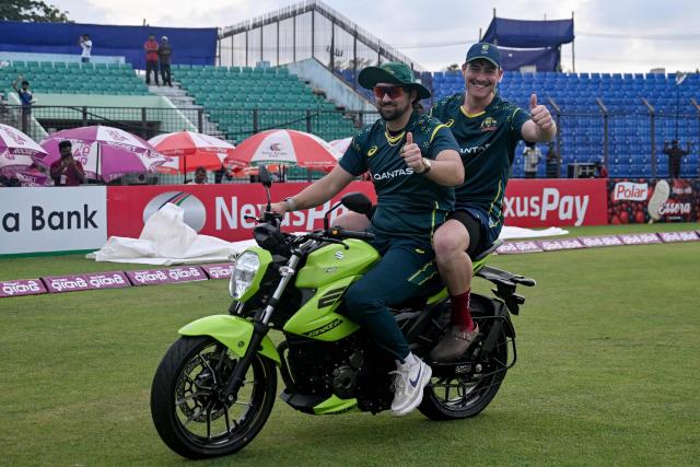 Australia's Tim David (L) and Matt Renshaw ride a motorbike during a victory lap to celebrate their team's win against Bangladesh at the end of their third Twenty20 (T20) international cricket match in the Bir Sreshtho Flight Lieutenant Matiur Rahman Stadium of Chattogram on June 21, 2026. (Photo by AFP)