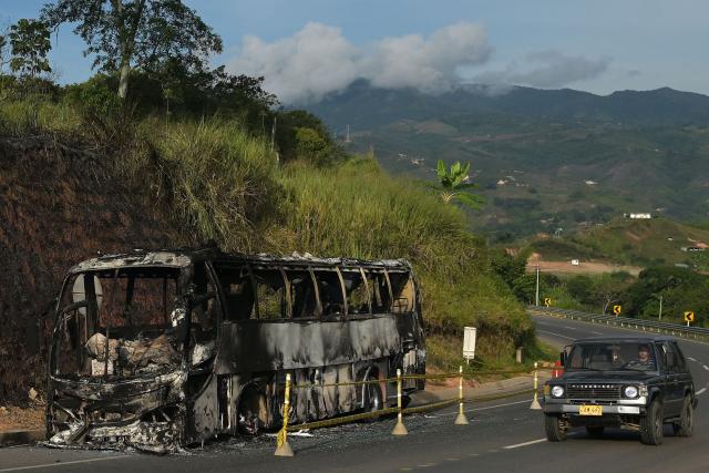 A car drives past a bus burnt by unidentified masked men in the Cali-Popayan highway hours before polls open for the presidential election runoff, near Cali, Valle del Cauca, Colombia, on June 21, 2026. Colombians head to the polls to pick a new president between a hard-right White House-backed lawyer and a leftist senator that will decide the fate of the country's stumbling peace process and strained ties with Washington. (Photo by JOAQUIN SARMIENTO / AFP)