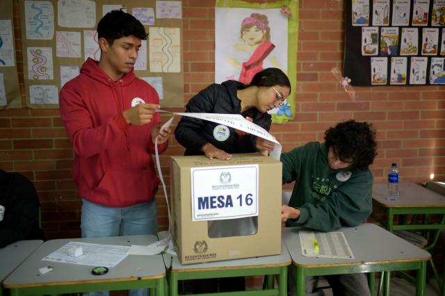 Workers prepare electoral material at a polling station before polls open for the presidential election runoff, in Bogota on June 21, 2026. Colombians head to the polls to pick a new president between a hard-right White House-backed lawyer and a leftist senator that will decide the fate of the country's stumbling peace process and strained ties with Washington. (Photo by Sebastian BARROS / AFP)