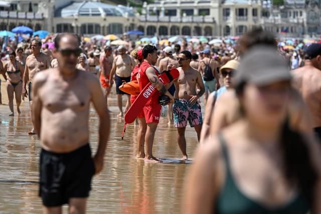 A man speaks with lifeguards at La Concha beach in the Spanish Basque city of San Sebastian, on June 21, 2026, first day of the first official heatwave of this summer. Spain's first official heatwave of this summer begins today and will last until at least June 24, 2026. The State Meteorological Agency (Aemet), the body responsible for declaring these types of episodes when they meet specific criteria regarding intensity, duration, and territorial extension, activated a special weather warning two days ago. (Photo by ANDER GILLENEA / AFP)