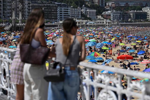 People pack La Concha bay beach in the Spanish Basque city of San Sebastian, on June 21, 2026, first day of the first official heatwave of this summer. Spain's first official heatwave of this summer begins today and will last until at least June 24, 2026. The State Meteorological Agency (Aemet), the body responsible for declaring these types of episodes when they meet specific criteria regarding intensity, duration, and territorial extension, activated a special weather warning two days ago. (Photo by ANDER GILLENEA / AFP)
