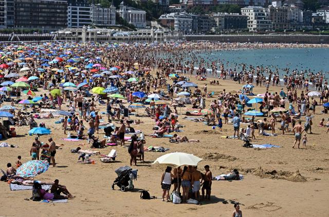 People pack La Concha beach in the Spanish Basque city of San Sebastian, on June 21, 2026 first day of the first official heatwave of this summer. Spain's first official heatwave of this summer begins today and will last until at least June 24, 2026. The State Meteorological Agency (Aemet), the body responsible for declaring these types of episodes when they meet specific criteria regarding intensity, duration, and territorial extension, activated a special weather warning two days ago. (Photo by ANDER GILLENEA / AFP)