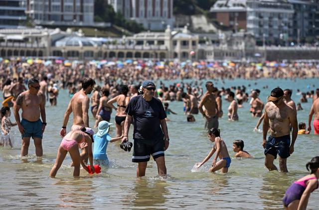People cool off in La Concha beach's water in the Spanish Basque city of San Sebastian, on June 21, 2026, first day of the first official heatwave of this summer. Spain's first official heatwave of this summer begins today and will last until at least June 24, 2026. The State Meteorological Agency (Aemet), the body responsible for declaring these types of episodes when they meet specific criteria regarding intensity, duration, and territorial extension, activated a special weather warning two days ago. (Photo by ANDER GILLENEA / AFP)