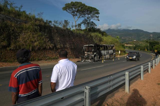 Locals stare at a bus burnt by unidentified masked men in the Cali-Popayan highway hours before polls open for the presidential election runoff, near Cali, Valle del Cauca, Colombia, on June 21, 2026. Colombians head to the polls to pick a new president between a hard-right White House-backed lawyer and a leftist senator that will decide the fate of the country's stumbling peace process and strained ties with Washington. (Photo by JOAQUIN SARMIENTO / AFP)