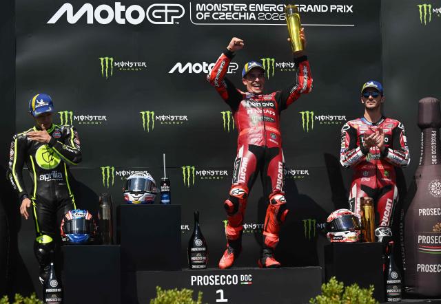 Winner Team Ducati Lenovo Team's Marc Marquez (C) celebrates on the podium and is applauded by second placed Team Trackhouse Racing MotoGP's Ai Ogura (L) and third placed Team Ducati Lenovo Team's Francesco Bagnaia (R) after the MotoGP Grand Prix of Czechia in Brno, Czech Republic, on June 21, 2026. (Photo by Michal Cizek / AFP)