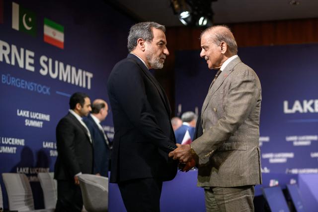 Iran's Foreign Minister Abbas Araghchi (L) shakes hands with Pakistan's Prime Minister Shehbaz Sharif ahead of a quadrilateral meeting between the United States, Iran, Pakistan and Qatar at the Burgenstock luxury hotel complex overlooking Lake Lucerne, Switzerland, on June 21, 2026, as part of high-level talks aimed at advancing a deal to end the Middle East conflict. A new round of negotiations over the Middle East war was set to kick off on June 21, 2026 with Iranian negotiators arriving in the Swiss host city hours ahead of US Vice President JD Vance, even as Tehran said it was closing the Strait of Hormuz again over Israeli attacks in Lebanon. (Photo by Fabrice Coffrini / POOL / AFP)