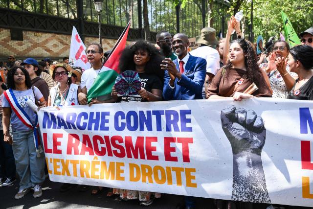 French activist and leader of the Truth and Justice for Adama Committee Assa Traore (C-L) and Saint-Denis Mayor Bally Bagayoko (R) hold a banner reading "Walk against racism and far-right" take part in a rally against racism and far-right in Paris on June 21, 2026. (Photo by Arnaud FINISTRE / AFP)