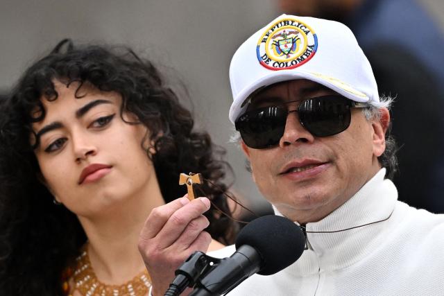 Colombia's President Gustavo Petro shows a Taw (last letter of the Aramaic alphabet) as he speaks next to his daughter Sofia at a polling station during the presidential election runoff, in Bogota on June 21, 2026. Colombians head to the polls to pick a new president between a hard-right White House-backed lawyer and a leftist senator that will decide the fate of the country's stumbling peace process and strained ties with Washington. (Photo by Luis ACOSTA / AFP)