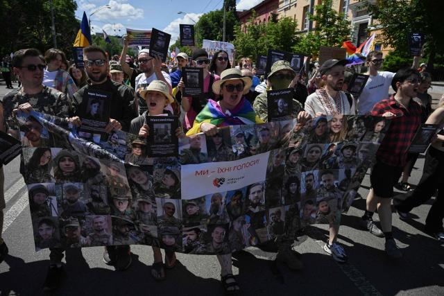 Demonstrators hold a banner with portraits of army service members part of the LGTQ community during the Kyiv Pride Equality March, a rally in support of the rights of LGBTQ+ community members, in Kyiv on June 21, 2026, amid the Russian invasion of Ukraine. (Photo by Genya SAVILOV / AFP)