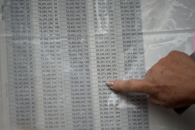 A woman points at a number in a electoral roll at a polling station during the presidential election runoff, in Bogota on June 21, 2026. Colombians head to the polls to pick a new president between a hard-right White House-backed lawyer and a leftist senator that will decide the fate of the country's stumbling peace process and strained ties with Washington. (Photo by Sebastian BARROS / AFP)