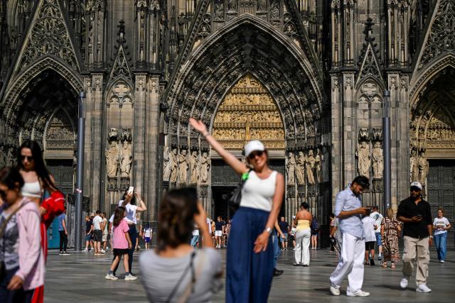 Tourists pose in front of the Cologne cathedral, western Germany on June 21, 2026. From July 1, 2026 tourists will only be able to enter the interior of Cologne Cathedral after purchasing a ticket. Attendance at church services will remain free of charge without restriction. (Photo by Ina FASSBENDER / AFP)