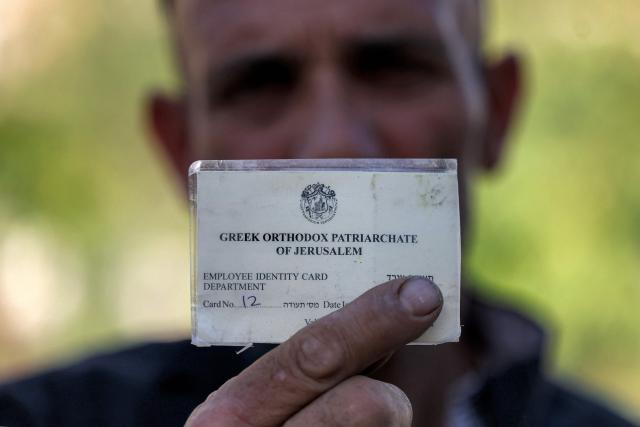 Khaled al-Zeer, resident of the Arab neighbourhood of Silwan in Israeli-annexed east Jerusalem, presents his Greek Orthodox Patriarchate employee identity card, as he stands in Silwan on June 21, 2026. The Greek Orthodox Patriarchate of Jerusalem on June 17 denounced what it described as an "unlawful and illegitimate" Israeli seizure of its property in the eastern part of the city earlier in the week. In a statement, it also that during the operation, which took place on June 15, "the Patriarchate's representative was forcibly removed, his equipment was confiscated, trees were uprooted, and the property was enclosed with fencing and gates". (Photo by HAZEM BADER / AFP)