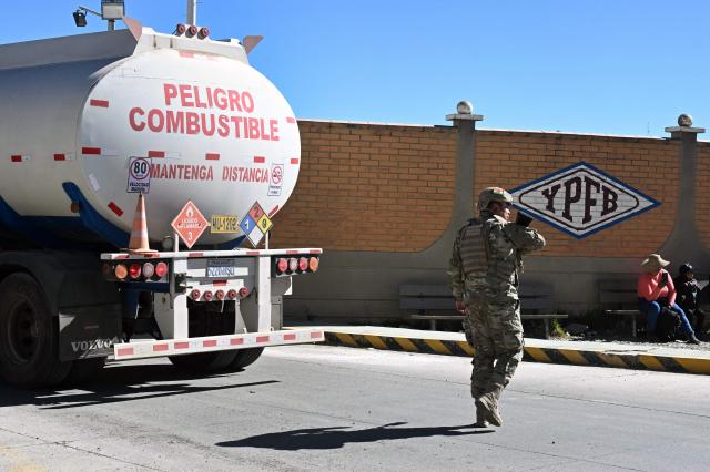 A Bolivian soldier stands guard as a tank truck enters the state-owned Yacimientos Petrolíferos Fiscales Bolivianos (YPFB) Senkata plant, in El Alto, Bolivia, on June 21, 2026, a day after Bolivia's President Rodrigo Paz declared a state of emergency. Bolivian police driving bulldozers cleared highways and fuel trucks rolled into La Paz after the president declared a state of emergency to remove anti-government roadblocks promoted by unions, Indigenous groups, and coca growers that had paralyzed the Andean nation for more than six weeks. (Photo by AIZAR RALDES / AFP)