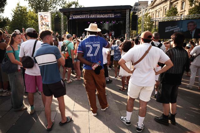 A man, wearing the French football jersey named after th founder of French left-wing party La France Insoumise (LFI) Jean-Luc Melenchon, attends a concert organised by French left-wing La France Insoumise (LFI) party as part of the annual street music festival 'Fete de la Musique' in Paris on June 21, 2026. (Photo by Guillaume BAPTISTE / AFP)