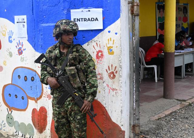 A soldier stands guard outside a polling center during the presidential election runoff, in Villa Paz, Valle del Cauca, Colombia, on June 21, 2026. Colombians head to the polls to pick a new president between a hard-right White House-backed lawyer and a leftist senator that will decide the fate of the country's stumbling peace process and strained ties with Washington. (Photo by Joaquin SARMIENTO / AFP)