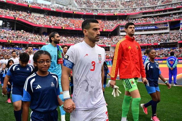 Iran's defender #03 Ehsan Hajsafi and Belgium's goalkeeper #01 Thibaut Courtois enter the pitch ahead of the 2026 World Cup Group G football match between Belgium and Iran at the Los Angeles Stadium in Inglewood on June 21, 2026.  (Photo by Frederic J. Brown / AFP)