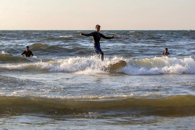 A youth stands on a surfboard amidst the waves off a beach in Gaza City on June 21, 2026. The ceasefire between Israel and the Palestinian Islamist movement Hamas came into effect in Gaza in October 2025 after two years of devastating war. But the tiny coastal territory remains gripped by bloodshed, with each side accusing the other of near-daily violations. (Photo by Omar AL-QATTAA / AFP)