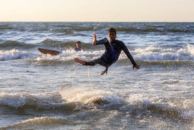 A youth falls off a surfboard amidst the waves off a beach in Gaza City on June 21, 2026. The ceasefire between Israel and the Palestinian Islamist movement Hamas came into effect in Gaza in October 2025 after two years of devastating war. But the tiny coastal territory remains gripped by bloodshed, with each side accusing the other of near-daily violations. (Photo by Omar AL-QATTAA / AFP)