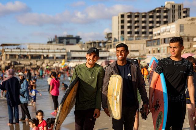 Youths walk with surfboards along a beach by the Mediterranean sea in Gaza City on June 21, 2026. The ceasefire between Israel and the Palestinian Islamist movement Hamas came into effect in Gaza in October 2025 after two years of devastating war. But the tiny coastal territory remains gripped by bloodshed, with each side accusing the other of near-daily violations. (Photo by Omar AL-QATTAA / AFP)