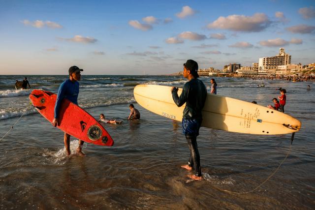 Youths stand with their surfboards in the surf of the Mediterranean sea off a beach in Gaza City on June 21, 2026. The ceasefire between Israel and the Palestinian Islamist movement Hamas came into effect in Gaza in October 2025 after two years of devastating war. But the tiny coastal territory remains gripped by bloodshed, with each side accusing the other of near-daily violations. (Photo by Omar AL-QATTAA / AFP)