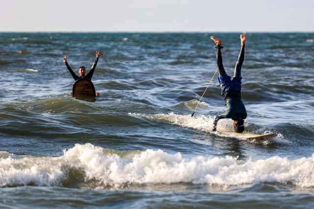 Youths perform stunts with their surfboards in the Mediterranean sea off a beach in Gaza City on June 21, 2026. The ceasefire between Israel and the Palestinian Islamist movement Hamas came into effect in Gaza in October 2025 after two years of devastating war. But the tiny coastal territory remains gripped by bloodshed, with each side accusing the other of near-daily violations. (Photo by Omar AL-QATTAA / AFP)