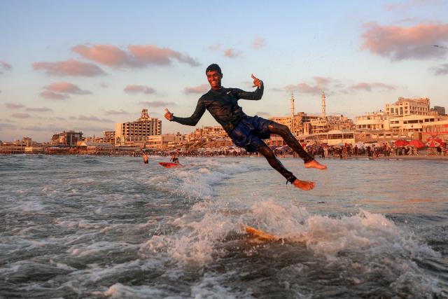 A youth jumps off a surfboard amidst the waves off a beach in Gaza City on June 21, 2026. The ceasefire between Israel and the Palestinian Islamist movement Hamas came into effect in Gaza in October 2025 after two years of devastating war. But the tiny coastal territory remains gripped by bloodshed, with each side accusing the other of near-daily violations. (Photo by Omar AL-QATTAA / AFP)