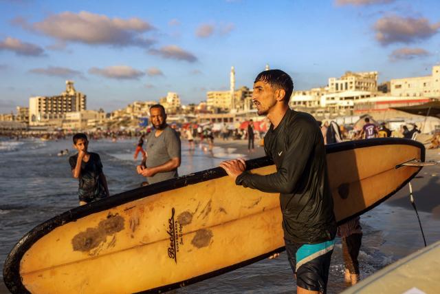 Palestinian surfer Hussein Abu Assi, 23, takes his surfboard out into the Mediterranean sea off a beach in Gaza City on June 21, 2026. The ceasefire between Israel and the Palestinian Islamist movement Hamas came into effect in Gaza in October 2025 after two years of devastating war. But the tiny coastal territory remains gripped by bloodshed, with each side accusing the other of near-daily violations. (Photo by Omar AL-QATTAA / AFP)
