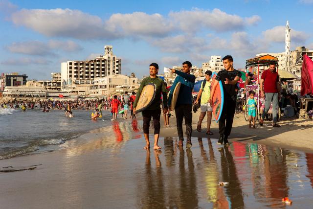 Youths walk with surfboards along a beach by the Mediterranean sea in Gaza City on June 21, 2026. The ceasefire between Israel and the Palestinian Islamist movement Hamas came into effect in Gaza in October 2025 after two years of devastating war. But the tiny coastal territory remains gripped by bloodshed, with each side accusing the other of near-daily violations. (Photo by Omar AL-QATTAA / AFP)