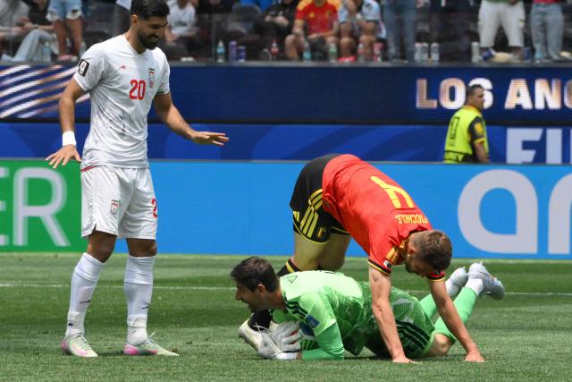 Belgium's goalkeeper #01 Thibaut Courtois holds the ball as teammate Belgium's defender #04 Brandon Mechele falls over him next to Iran's forward #20 Shahriyar Moghanloo during the 2026 World Cup Group G football match between Belgium and Iran at the Los Angeles Stadium in Inglewood on June 21, 2026.  (Photo by Patrick T. Fallon / AFP)