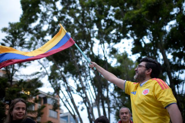 A supporters of Colombia's presidential candidate for the Defensores de la Patria movement Abelardo de la Espriella waves a national flag as he celebrates the results of the presidential runoff election in Cali, Colombia, on June 21, 2026. A flamboyant US-backed lawyer who has never held public office narrowly won Colombia's presidential runoff on June 21, swinging the country hard to the right on a promise to wage war against drug-running guerrilla groups. With more than 99 percent of polling centers reporting, Abelardo de la Espriella had 49.67 percent of the vote, an unassailable lead over his rival, left-wing Senator Ivan Cepeda who trailed at 48.69 percent, according to official results. (Photo by Sebastian BARROS / AFP)