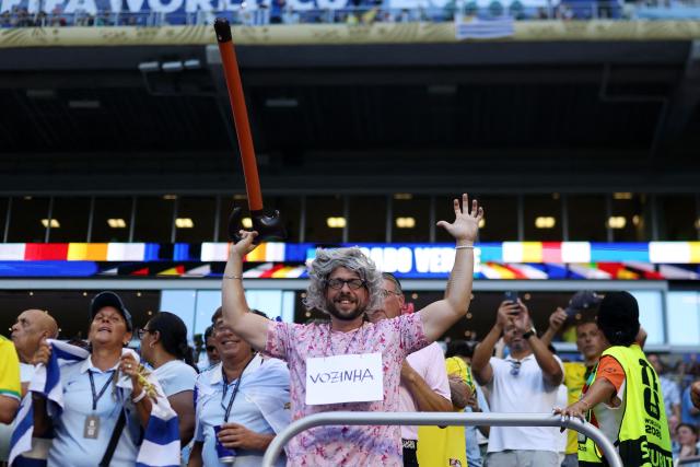 A fan wearing a sign that reads "Vozinha" gestures during the 2026 World Cup Group H football match between Uruguay and Cape Verde at the Miami Stadium in Miami Gardens on June 21, 2026.  (Photo by PATRICIA DE MELO MOREIRA / AFP)
