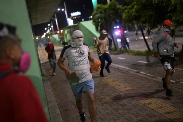 Supporters of Colombia's presidential candidate Ivan Cepeda of the ruling Pacto Historico party run from tear gas as they protest the results of the presidential runoff election in Cali, Colombia, on June 21, 2026. A flamboyant US-backed lawyer who has never held public office narrowly won Colombia's presidential runoff Sunday, swinging the country hard to the right on a promise to wage war against drug-running guerrilla groups. With more than 99 percent of polling centers reporting, Abelardo de la Espriella had 49.67 percent of the vote, an unassailable lead over his rival, left-wing Senator Ivan Cepeda who trailed at 48.69 percent, according to official results. (Photo by JOAQUIN SARMIENTO / AFP)