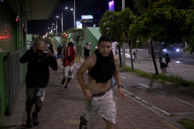 Supporters of Colombias presidential candidate Ivan Cepeda of the ruling Pacto Historico party run along a sidewalk as riot police give chase during a protest following the presidential runoff election results in Cali, Colombia, on June 21, 2026. A flamboyant US-backed lawyer who has never held public office narrowly won Colombia's presidential runoff Sunday, swinging the country hard to the right on a promise to wage war against drug-running guerrilla groups. With more than 99 percent of polling centers reporting, Abelardo de la Espriella had 49.67 percent of the vote, an unassailable lead over his rival, left-wing Senator Ivan Cepeda who trailed at 48.69 percent, according to official results. (Photo by JOAQUIN SARMIENTO / AFP)