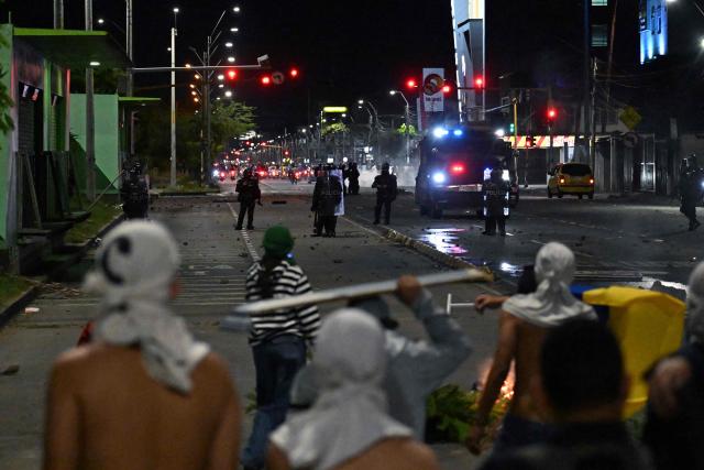 TOPSHOT - Demonstrators clash with riot police as they protest the preliminary results of the presidential runoff election in Cali, Colombia, on June 21, 2026. A flamboyant US-backed lawyer who has never held public office narrowly won Colombia's presidential runoff Sunday, swinging the country hard to the right on a promise to wage war against drug-running guerrilla groups. With more than 99 percent of polling centers reporting, Abelardo de la Espriella had 49.67 percent of the vote, an unassailable lead over his rival, left-wing Senator Ivan Cepeda who trailed at 48.69 percent, according to official results. (Photo by Joaquin SARMIENTO / AFP)